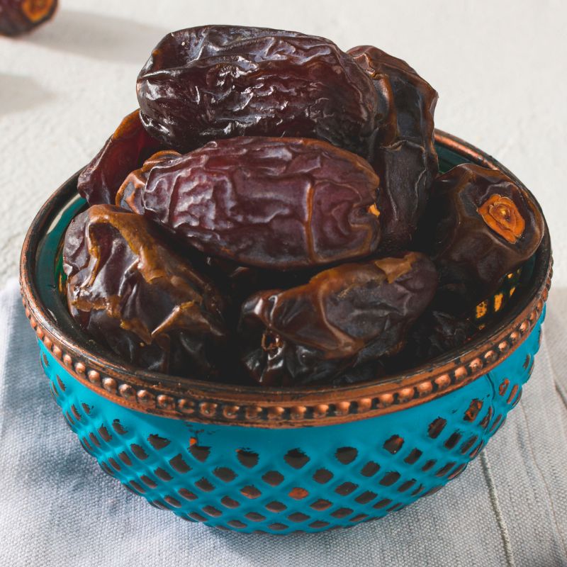 Medjool urme u plavoj činijici, slikane od gore iz kosine.