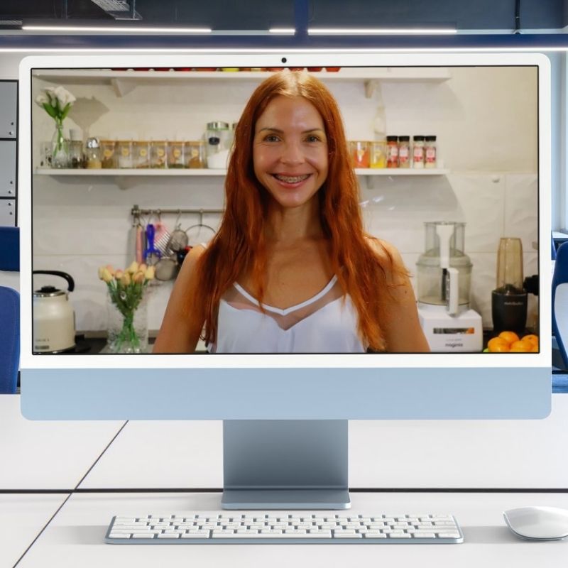 Slika Marine sa Billjne ishrane kako stoji u svojoj kuhinji i smeje se prema kameri nalazi se na ekranu desktopa koji stoji na radnom stolu. Ispred desktopa su tastuta i miš.