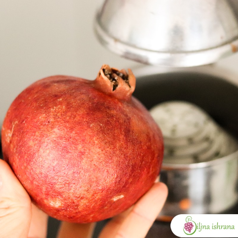 Nar u ljudskoj ruci, ispred prese za ceđenje nara.