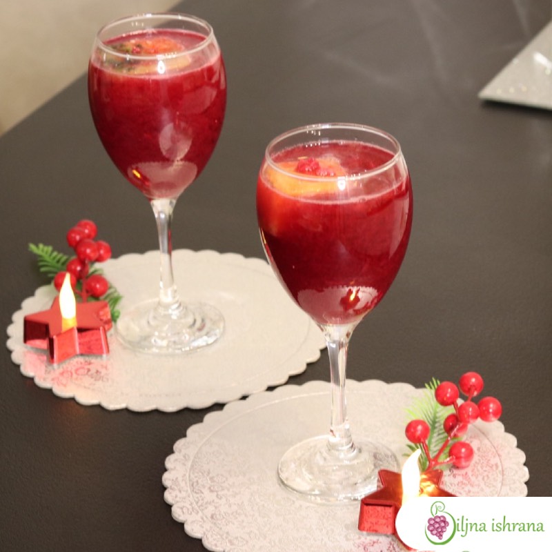 Vinske čaše pune soka od nara. Uz čaše se nalaze i božićne dekoracije.