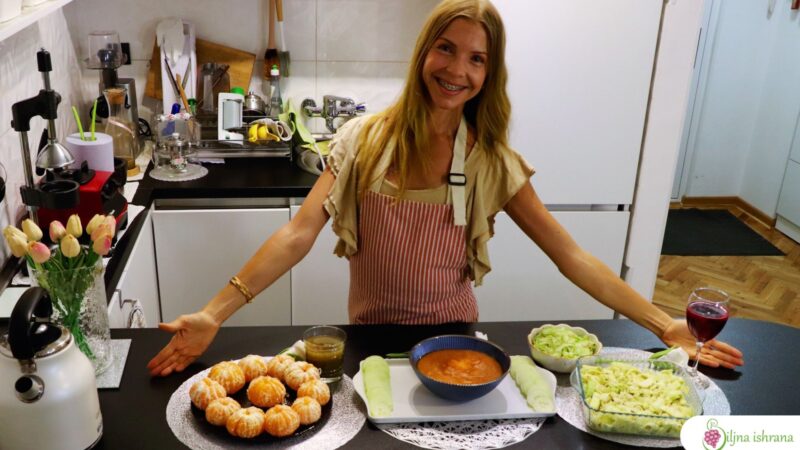 Marina sa Biljne ishrane stoji iza kuhinjskog pulta na kojem su tri sirova veganska obroka, predstavljajući onlajn program 'Jelovnik na sirovoj ishrani'.