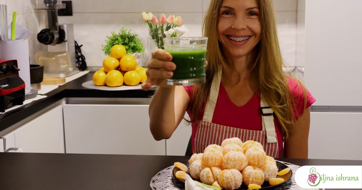 Marina sa Biljne ishrane sedi za stolom na kojem je poslužen sirov veganski doručak od klementina i zelenog soka.