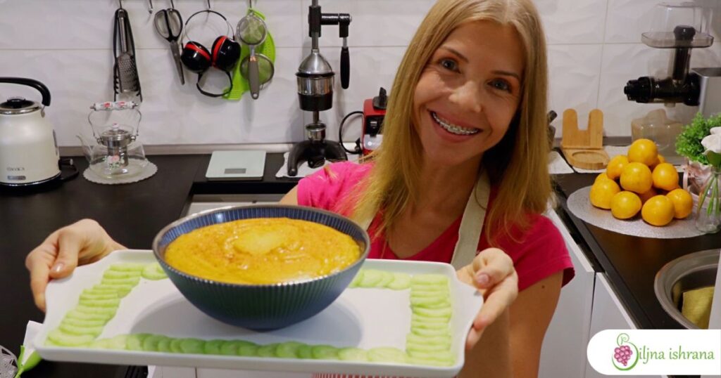 Marina sa Biljne ishrane drži belu tacnu na kojoj je činija sa pudingom od japanskih jabuka i tanki kolići krastavca.