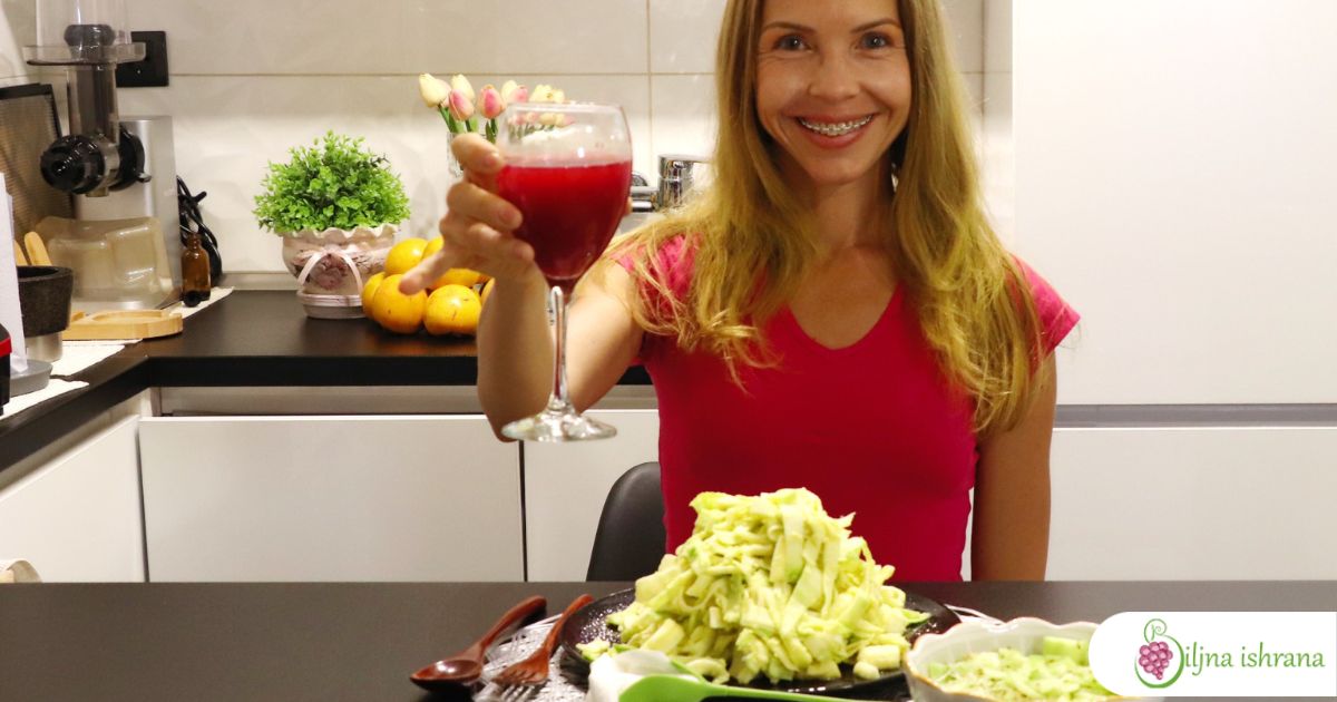 Marina sa Biljne ishrane sedi za stolom na kojem je poslužen sirova veganska večera od soka od nara, sirove veganske paste i salate od krastavaca i mikrobilja.