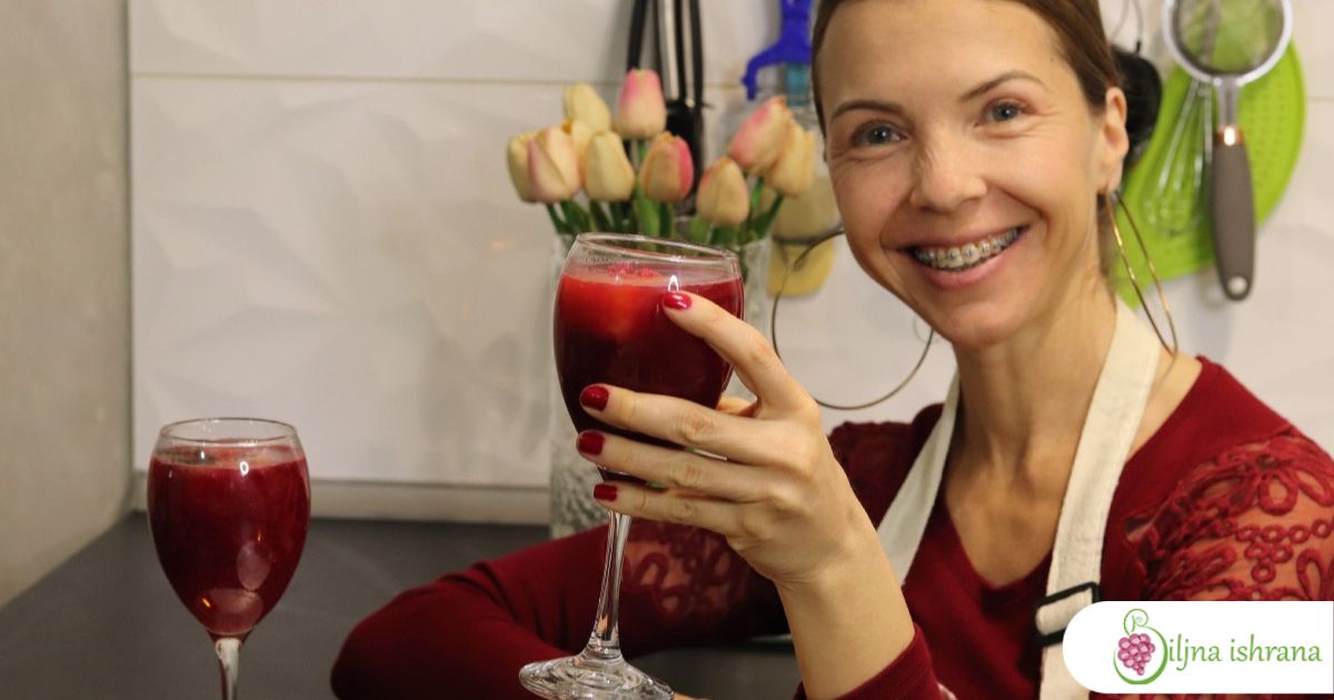 Marina sa Biljne ishrane sedi za stolom i drži jednu vinsku čašu u rucu. Čaša je puna soka od nara.