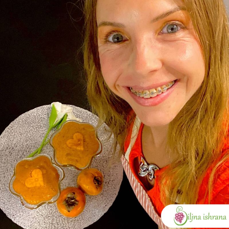 Marina sa Biljne ishrane pored kuhinjskog pulta na kojem su dve činije pune pudinga od japanskih jabuka. Ispred činija su dve cele japanske jabuke.